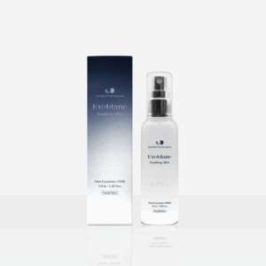A product image of Exoblanc Soothing Mist, a post-procedure facial mist for soothing and hydration. The photo displays a sleek white spray bottle with a fine mist nozzle, labeled "Exoblanc Soothing Mist" and "Facial Mist" in elegant black text, positioned in front of its navy blue rectangular box packaging. The box features the brand logo at the top, "Exoblanc" in white, "Soothing Mist" below, and details including "Post-Procedure Facial Mist," "100ml / 3.38 fl oz," and subtle performance icons at the bottom.